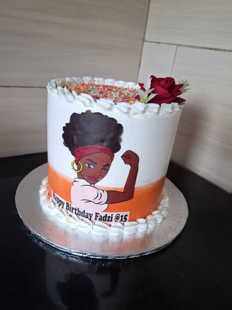 White and orange birthday cake with edible afro queen design
